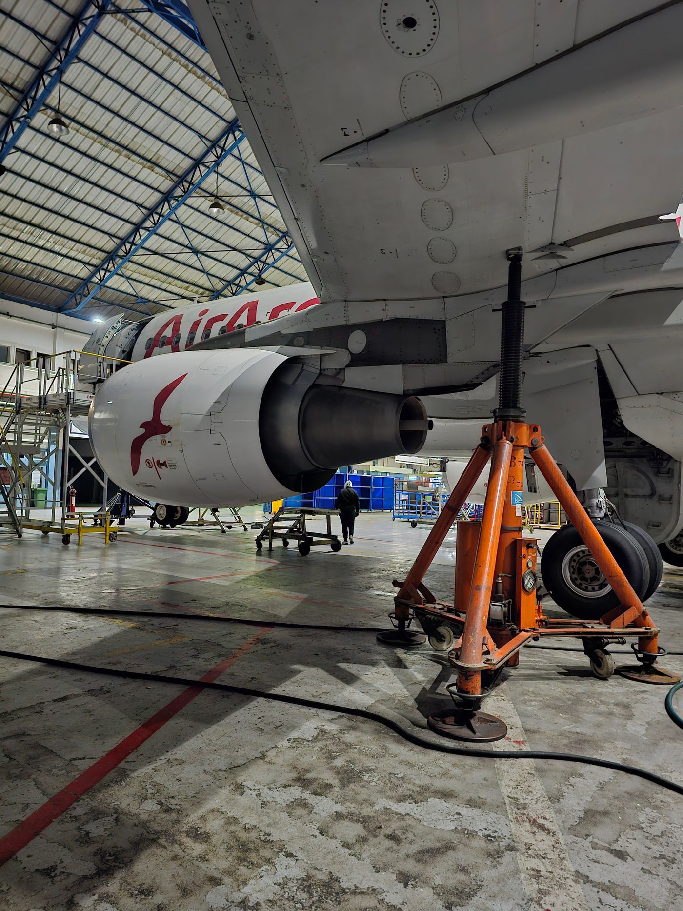A commercial aircraft on jacks undergoing base maintenance in an MRO hangar